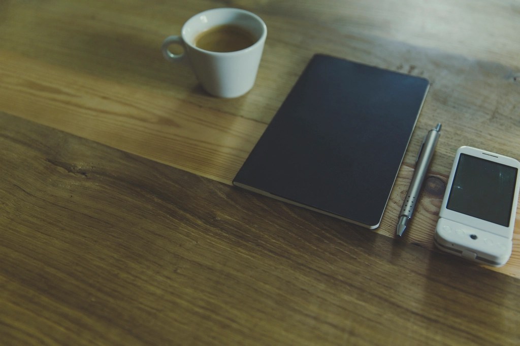 planner, coffee, pen, phone laid out on table